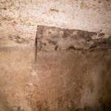 Su una parete notiamo una sagoma che pare raffigurare una porta murata. � probabile infatti che questo ambiente fosse un tempo collegato a uno pi� grande: quello che ospitava mille anni fa l�originaria Santa Maria dei Kyri Joannaci